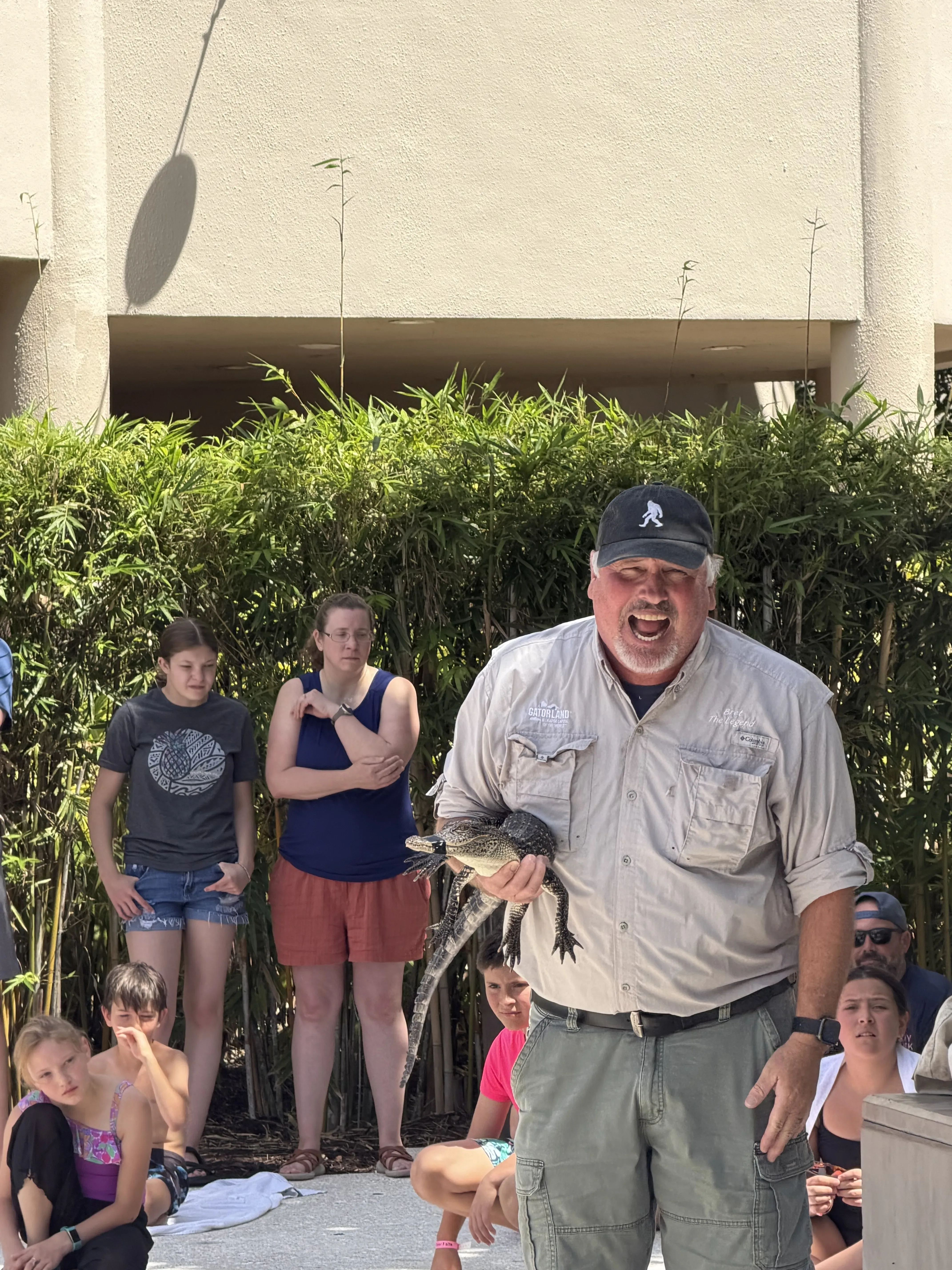 Gentleman holding a small alligator during wildlife show.